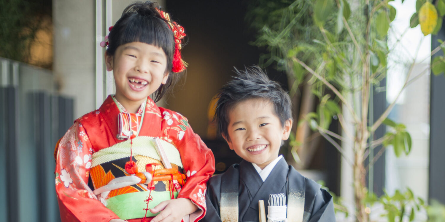 赤の着物を期待７歳の女の子と黒い袴を着た５歳の男の子が笑顔でこちらをみている