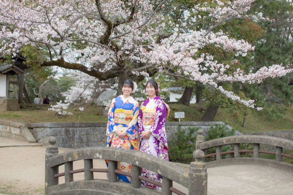 桜を背景に成人式の前撮りをする様子