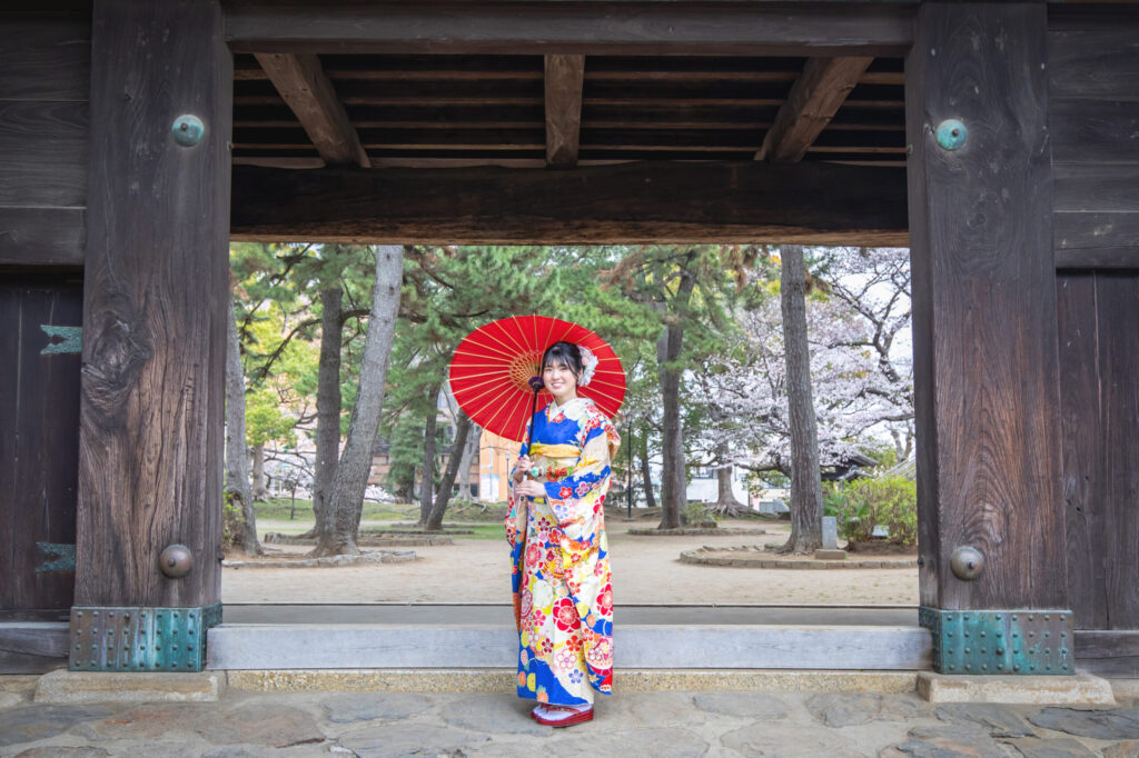 神社を背景に振袖姿を撮影する様子